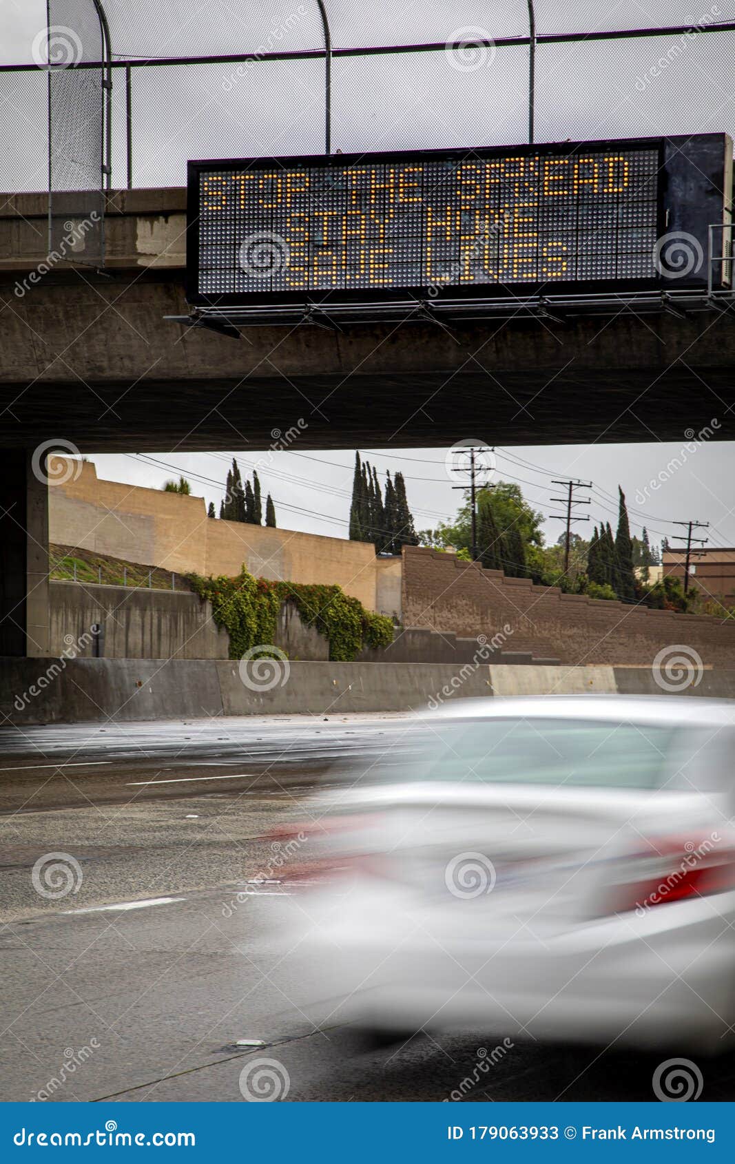 digital freeway sign at overpass with message stating Ã¢â¬Åstop the spread ,stay home, save livesÃ¢â¬Â and traffic blurred